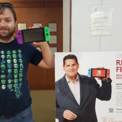 Me holding a Nintendo Switch next to a Reggie Fils-Aime poster 